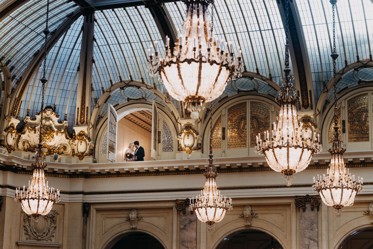 Bride and groom portrait with Garden Court chandeliers at the Palace Hotel San Francisco