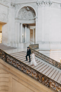 couple walking up grand staircase San Francisco City Hall wedding