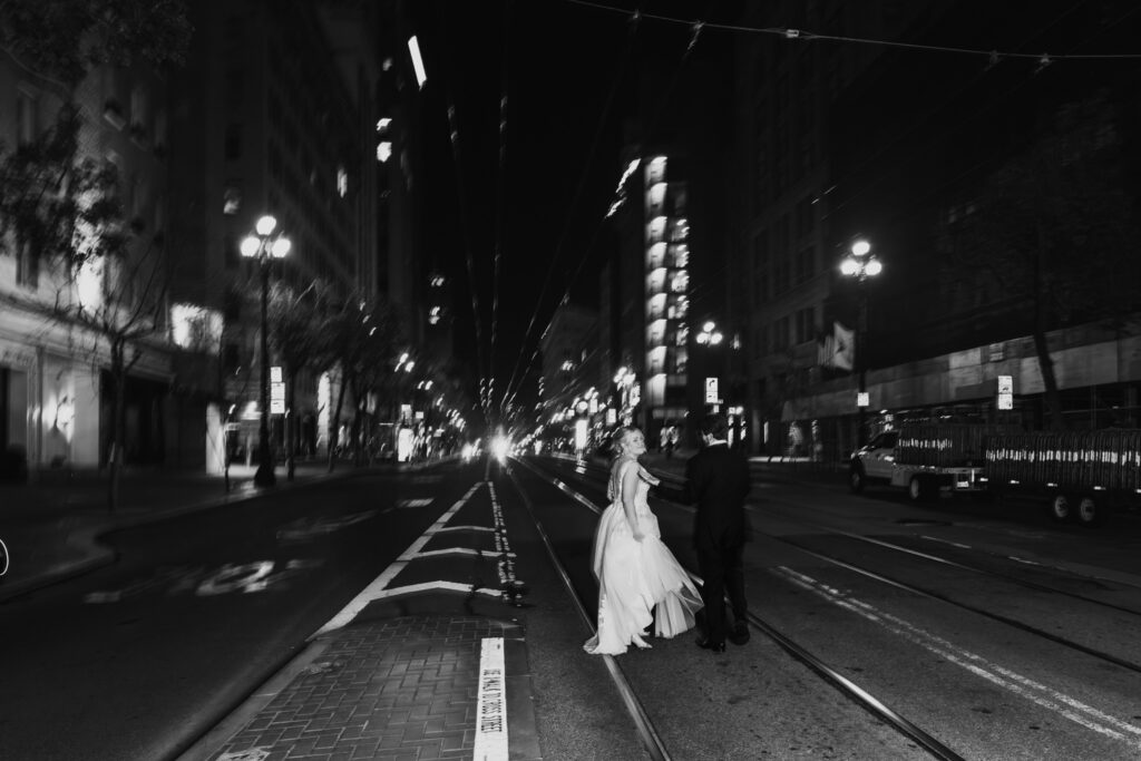 Couple portrait at night outside Palace Hotel San Francisco on Market Street with city lights