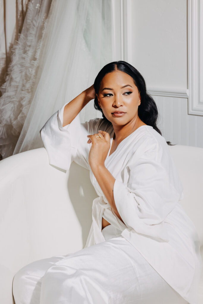 Black bride sitting in a clawfoot bathtub in her wedding pajamas, styled as a high-fashion vogue editorial portrait with dramatic lighting.