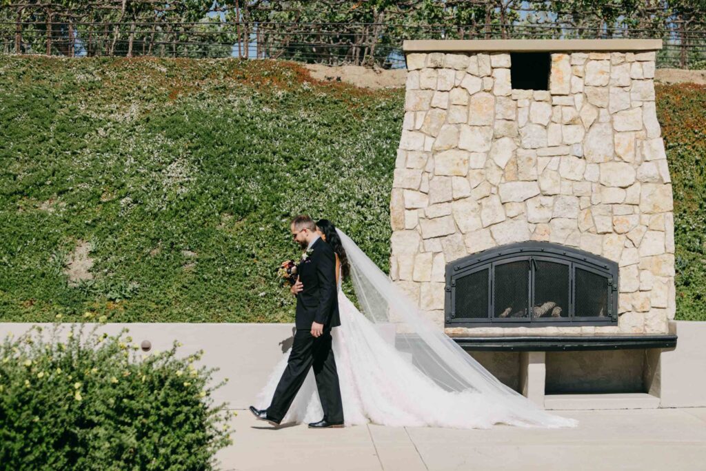 Black bride walking down the aisle at an outdoor vineyard wedding ceremony, guests standing on either side.