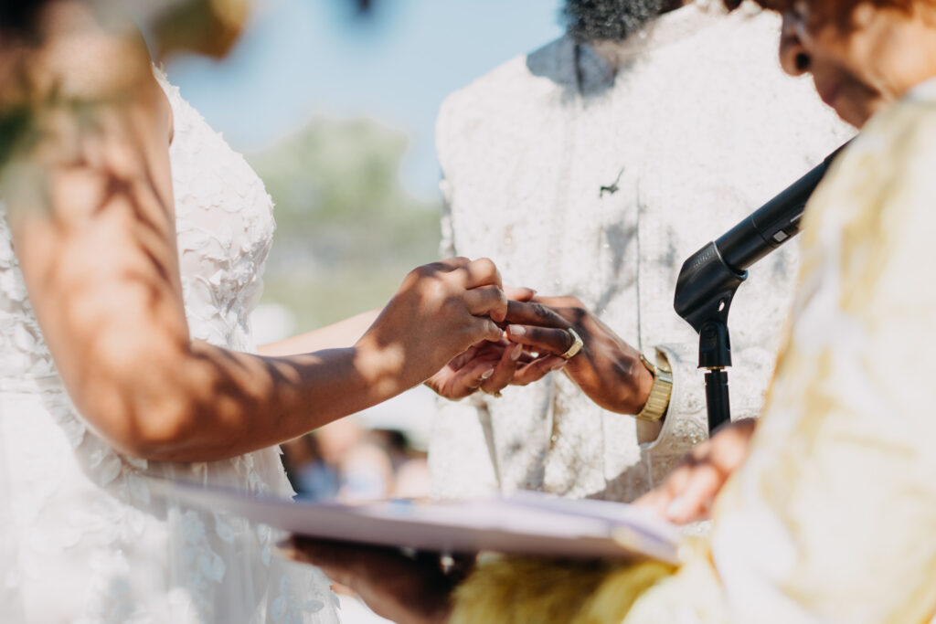 Close-up of the couple's hands during their wedding ring exchange at a vineyard ceremony.