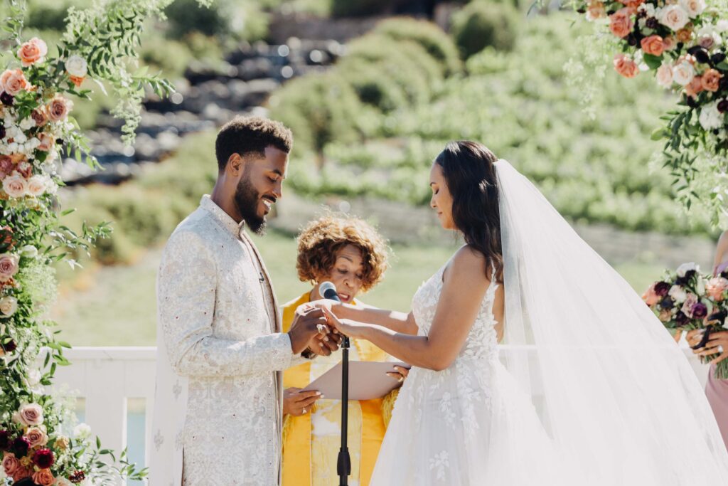 Close-up of the couple's hands during their wedding ring exchange at a vineyard ceremony.