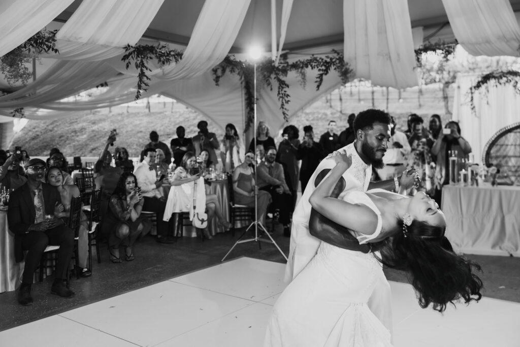Black bride and groom's first dance as a married couple under string lights at their vineyard reception.