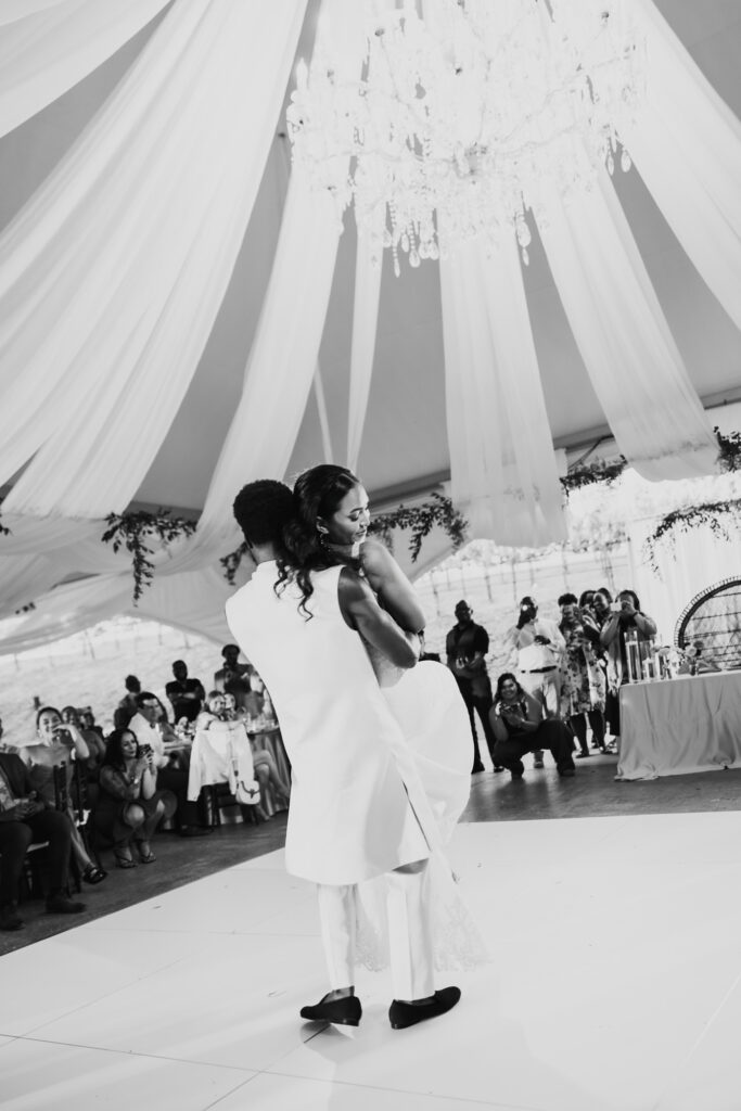Black bride and groom's first dance as a married couple under string lights at their vineyard reception.