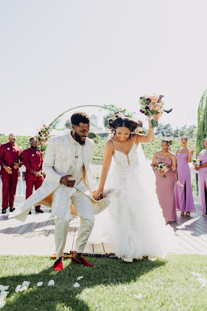 Black bride and groom jumping the broom at their vineyard wedding at Lavanda Leal Vineyards.
